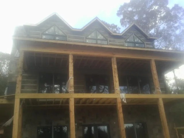 Dormers and porch framing on a large log home under construction — Roof Coating work by our crew in Winchester